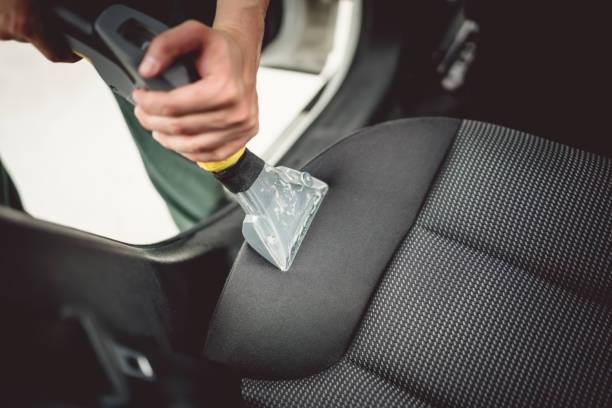 Technician cleaning a vehicle seat with an extractor