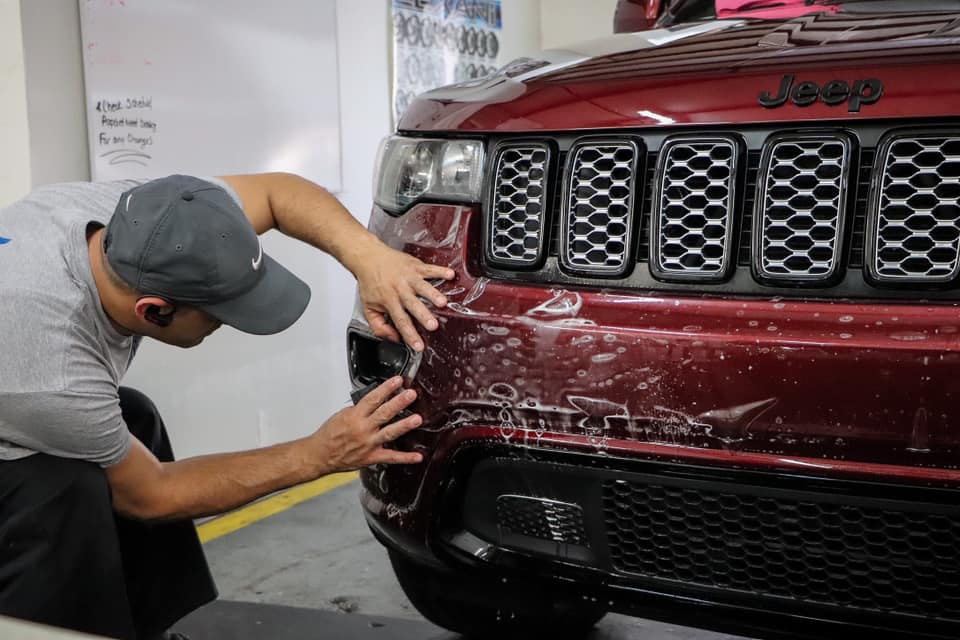 Technician applying paint protection film to a Jeep